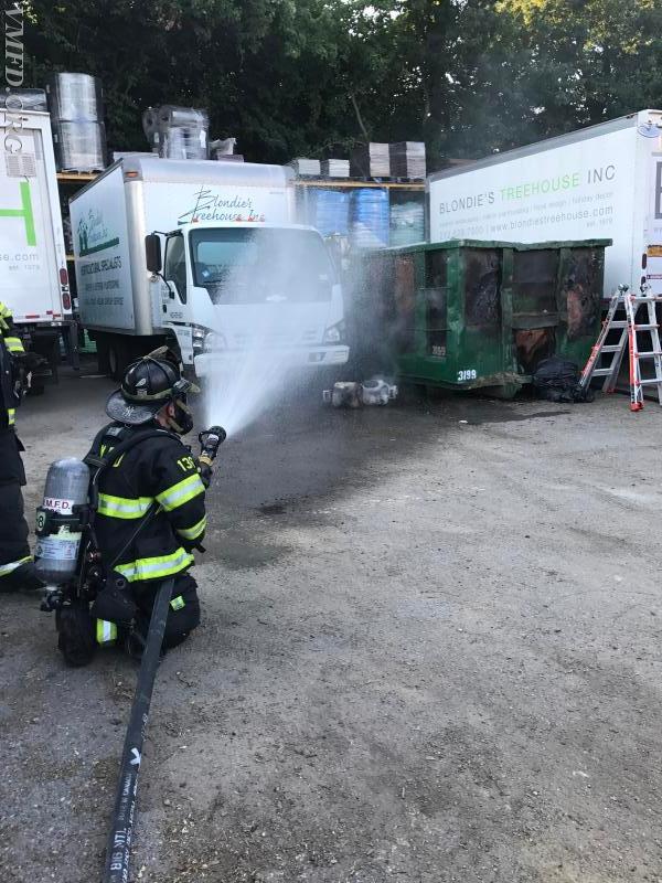 Captain Tom Seimsen of Engine 42 operates a secondary line protecting exposures next to a large dumpster fire.